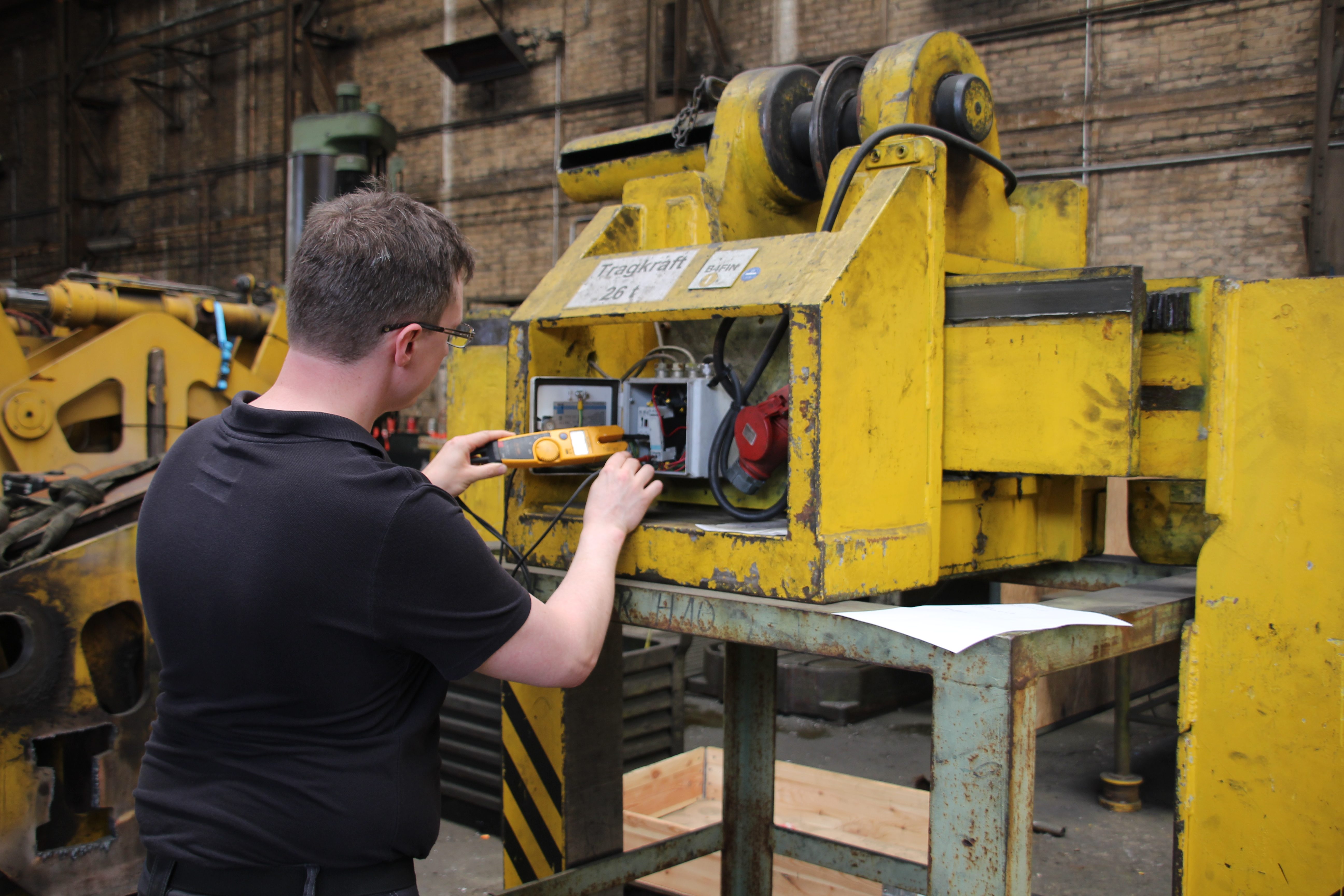 GvD-Elektroniker misst an der Steuerung einer Produktionsmaschine