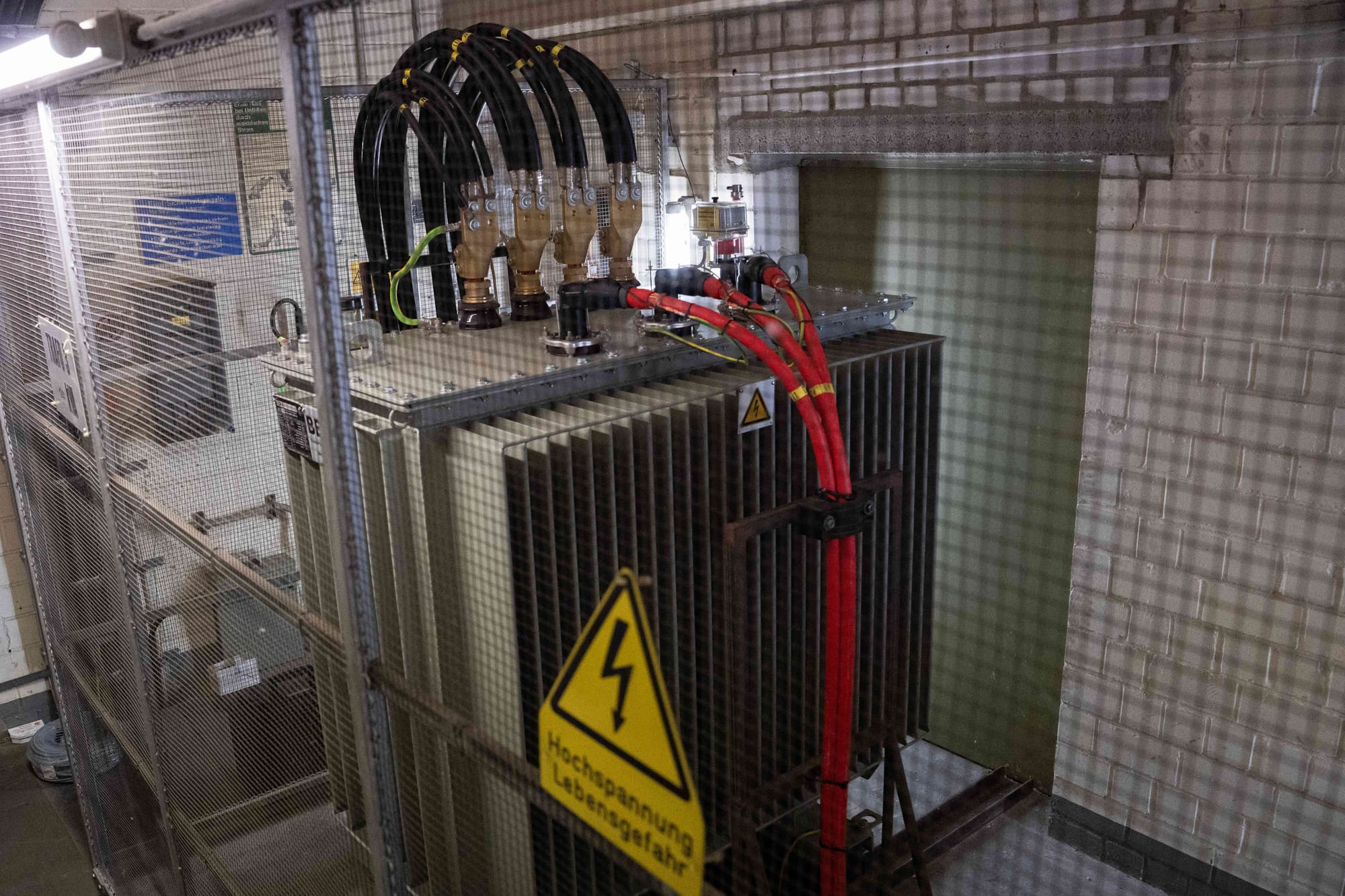 Angeschlossener Transformator hinter Schutzgitter mit Warnschild Hochspannung